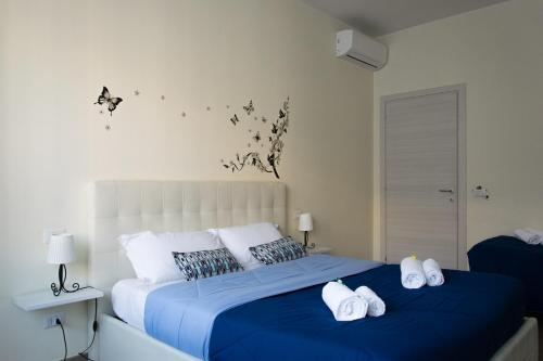 ヴェローナにあるMelibi - Re Lear Apartmentsのベッドルーム1室(青いシーツと蝶が壁に飾られたベッド1台付)