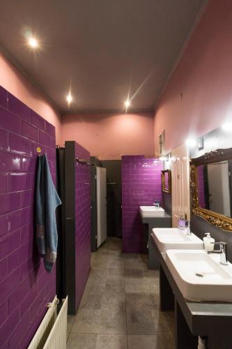 a purple bathroom with two sinks and two mirrors at Baroque Hostel & Coworking in Budapest