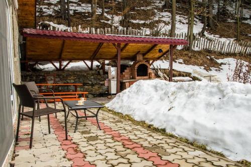 a patio with a table and a bench and snow at Casa Ozon in Vulcan