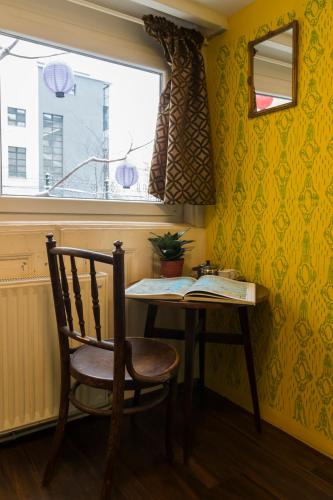 a table and a chair in a room with a window at Baroque Hostel & Coworking in Budapest