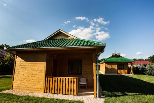 a small building with a green roof and a chair at Szatmár Beregi Élményliget in Fehérgyarmat