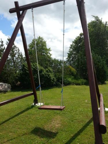 an empty swing in a field with a cross at "Lībieši" in Purmsāti