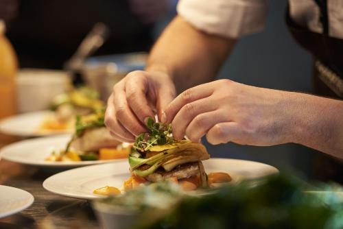 a person making a sandwich on a table with plates of food at Radhotel am Gleis in Radolfzell am Bodensee