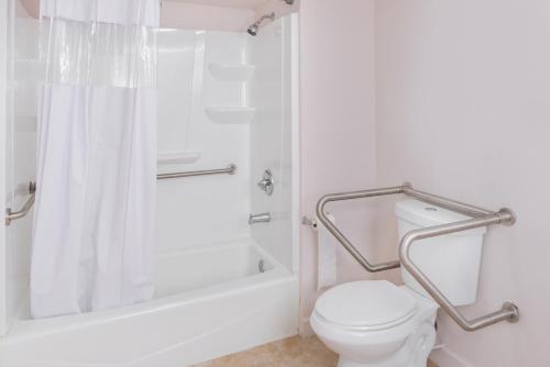 a white bathroom with a shower and a toilet at Motel Zuma in Williamsburg