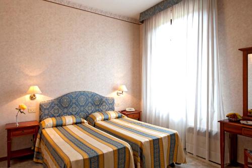 a hotel room with a bed and a window at Hotel Moderno in Siena