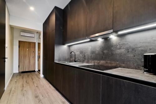 a kitchen with dark wood cabinets and a sink at City Center loft in Kaunas