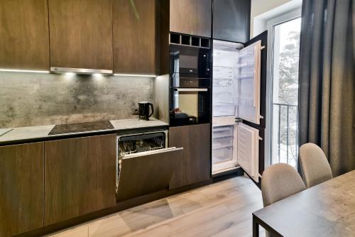 uma cozinha com armários de madeira escura e uma mesa em City Center loft em Kaunas