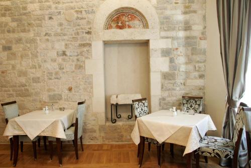 a dining room with two tables and a stone wall at Palace Augubio in Split