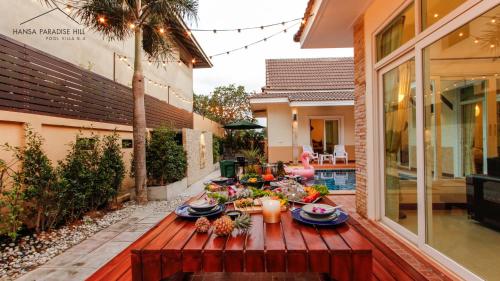 a wooden table with food and flowers on a patio at Hansa Paradise Hill Pool Villa in Nong Prue