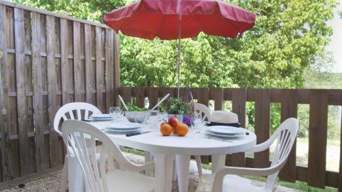 a white table with a red umbrella on a patio at VVF Lac d'Eguzon in Éguzon-Chantôme
