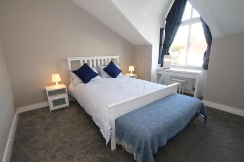 a bedroom with a white bed with blue pillows and a window at Strand House 2 in Portstewart