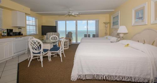 a bedroom with two beds and a table and a kitchen at Edison Beach House in Fort Myers Beach