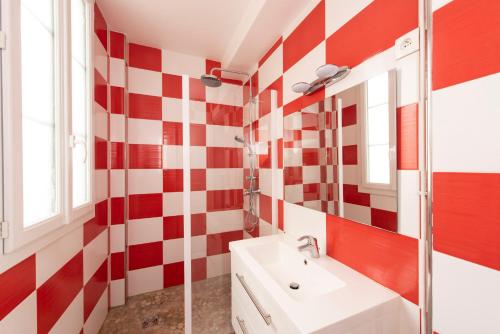 une salle de bain avec un mur à carreaux rouges et blancs dans l'établissement Objectif Lune, à Paris