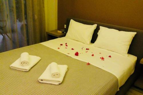 a bed with white towels and red flowers on it at New Luxury Apartments in Plakias in Plakias