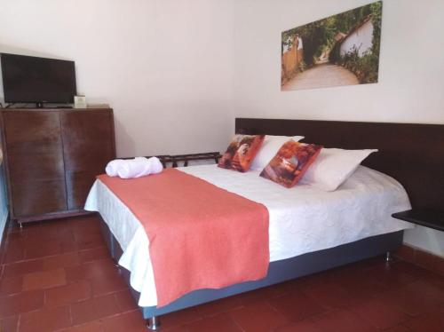 a bedroom with a bed with a red blanket on it at Hotel Casa del Marquez de Bahichala in Barichara