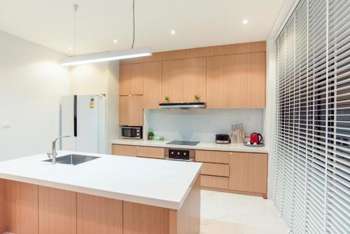 a kitchen with a white counter top and wooden cabinets at Vmoon villa chiangmai in Chiang Mai