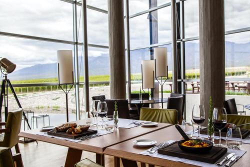a dining room with a table with food and wine glasses at Casa de Uco Vineyards and Wine Resort in Los Árboles
