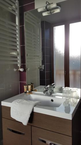 a bathroom with a sink and a mirror at Hôtel du Soleil in Aillon-le-Jeune