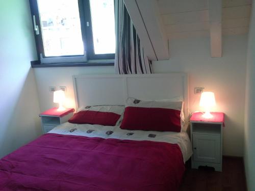 タルヴィージオにあるCasa Dello Scoiattolo Tarvisioのベッドルーム1室(赤い枕とランプ2つ付)