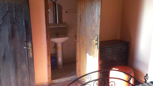 - une porte ouverte donnant sur une salle de bains avec lavabo dans l'établissement Riad Tifor, à Marrakech