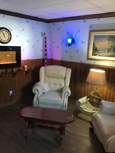 ein Wohnzimmer mit einem Stuhl, einem Tisch und einer Uhr in der Unterkunft Auberge La Cote d'Or in Petite-Rivière-Saint-François