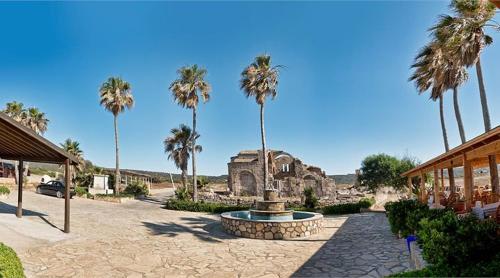 a courtyard with a fountain with palm trees and a building at OASİS AT AYFİLON in Rizokarpaso