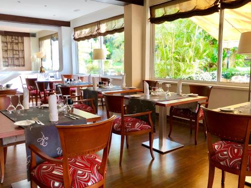 a dining room with tables and chairs and windows at Hotel Tigaiga in Puerto de la Cruz