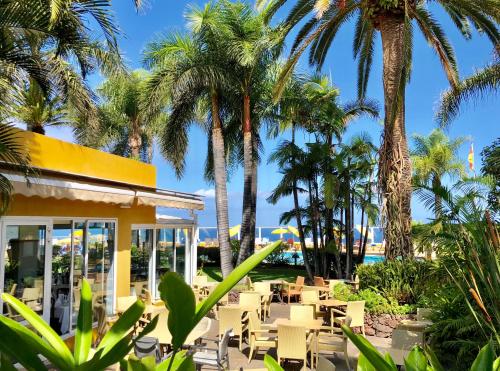a resort with palm trees and tables and chairs at Hotel Tigaiga in Puerto de la Cruz
