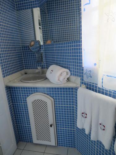 a blue tiled bathroom with a sink and a mirror at Recanto Serenissima in São Pedro