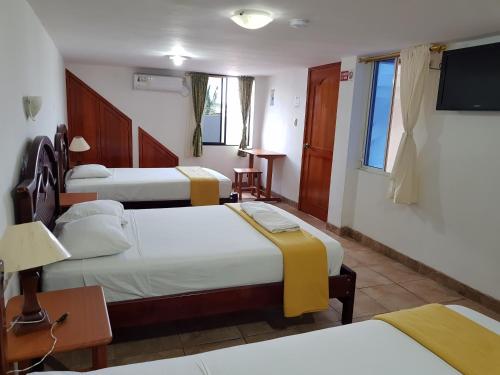 a hotel room with three beds and a flat screen tv at Gloria - Galápagos Inn in Puerto Ayora