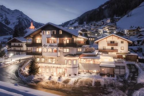 un grand bâtiment dans la neige la nuit dans l'établissement Hotel Mühlwald, à Selva dei Molini