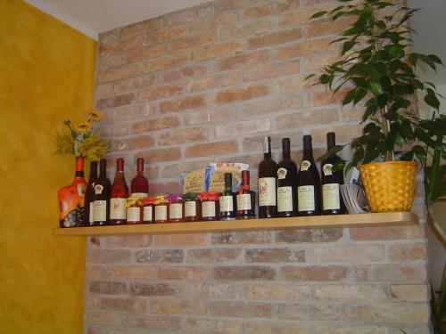 a shelf with wine bottles on a brick wall at La Via Del Volano in Codigoro