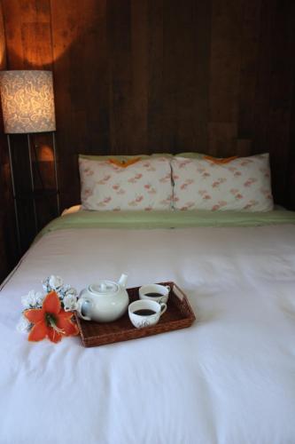 a tray with a tea set and flowers on a bed at Woodhouse Cottages And Ranch in Prince George