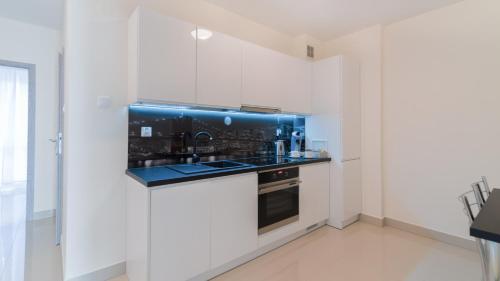 a white kitchen with a sink and a stove at Aparthotel Koroni Home in Raszyn