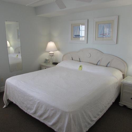 a bedroom with a large white bed and a mirror at Edison Beach House in Fort Myers Beach