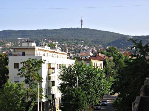 a white building with a hill in the background at Startpont Apartman in Pécs