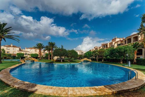 - une piscine dans un complexe avec des palmiers et des bâtiments dans l'établissement Bungavilla House in La Isla, à Jávea