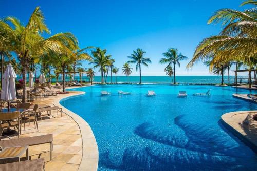 a large swimming pool with palm trees and the ocean at Wai Wai Cumbuco Eco Residence - Bahamas 101 in Cumbuco