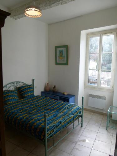 une chambre avec un lit avec une couette bleue et une fenêtre dans l'établissement Appartement au pied du gardon., à Remoulins