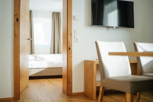 a room with a bedroom with a bed and a chair at Apartmenthaus Strasswirt De Luxe in Tröpolach