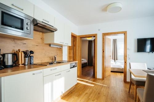 a kitchen with white cabinets and a living room at Apartmenthaus Strasswirt De Luxe in Tröpolach