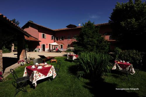 a garden with tables and chairs and a building at Agriturismo Il Gioco Dell'Oca in Barolo