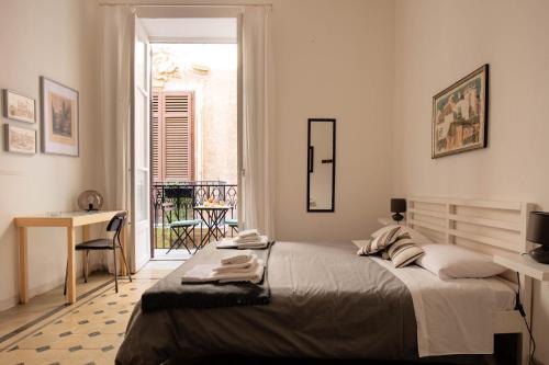 巴勒摩的住宿－La stanza del Vicolo，一间卧室配有一张床、一张书桌和一个窗户。