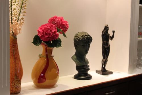 three vases with flowers and a statue on a shelf at Hotel Glockengasse in Cologne