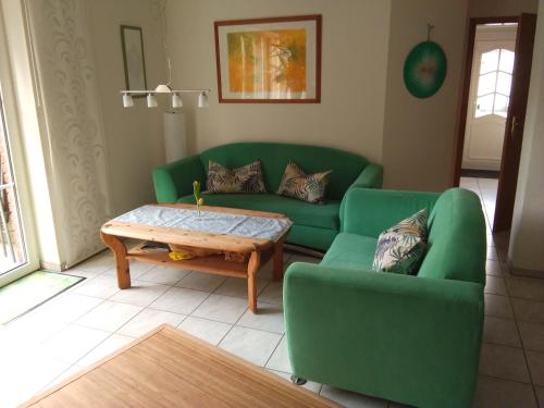 a living room with a green couch and a coffee table at Ferienwohnung Erlenhof in Engelskirchen