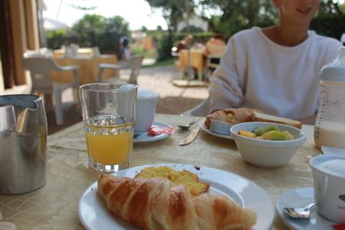 une table avec une assiette de nourriture et un verre de jus d'orange dans l'établissement Hotel Astor, à Lido di Classe