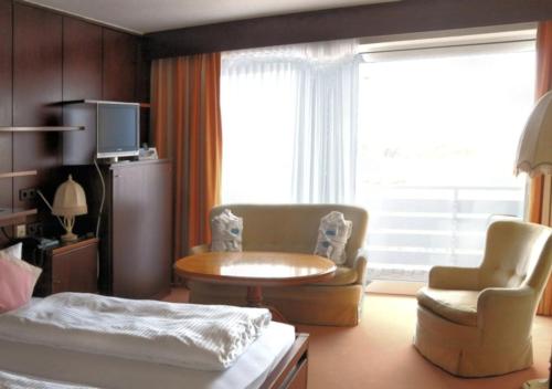 een slaapkamer met een bed, een tafel en een stoel bij Hotel das Miramar in Borkum