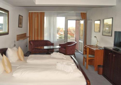 Habitación de hotel con cama, escritorio y TV. en Hotel das Miramar en Borkum