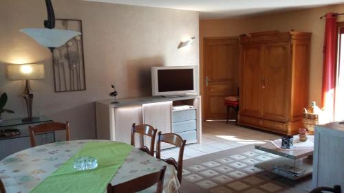 un salon avec une table et une télévision dans l'établissement vue sur les montagnes dans maison au calme, à Saint-Joseph-de-Rivière