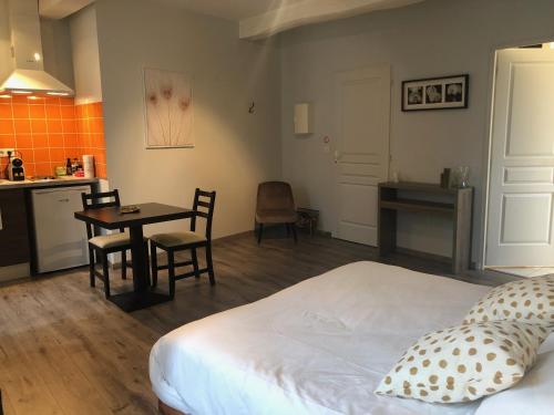 a bedroom with a bed and a table and a kitchen at Appart-Hôtel Résidence de Garonne in Tonneins